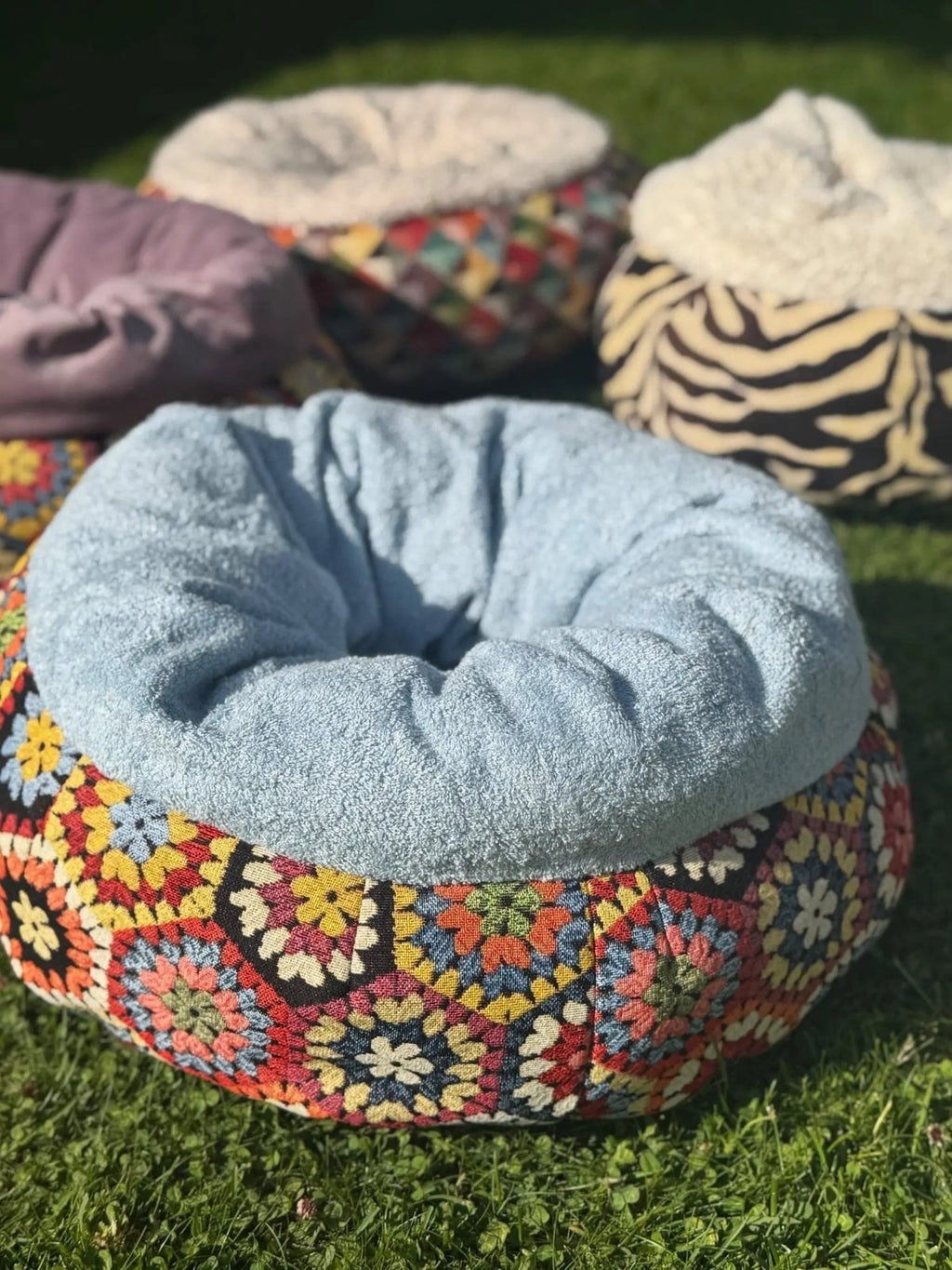 Colorful crocheted pet bed on grass with other pet beds in the background
